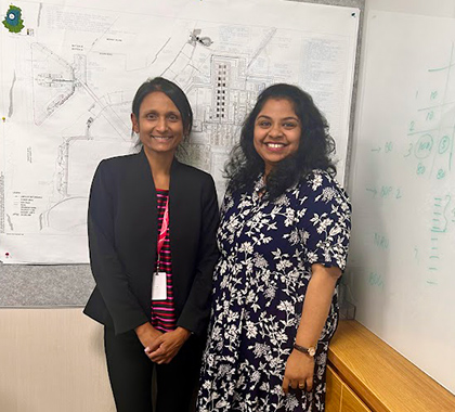 Snehal standing next to a colleague in front of a whiteboard.