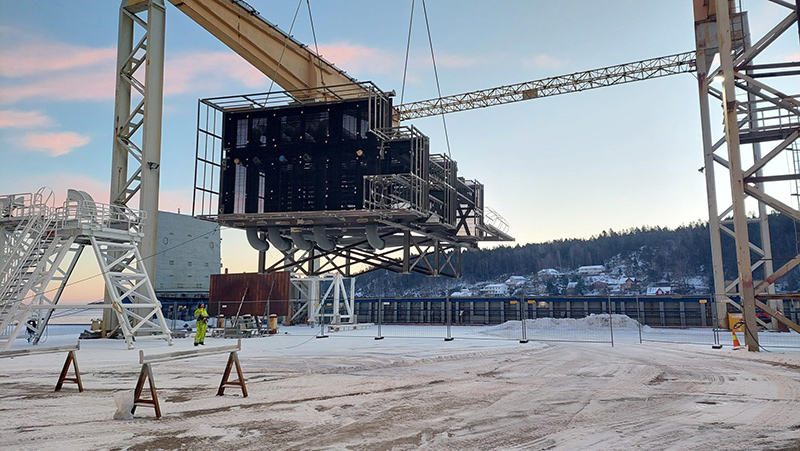 Floating Storage Regasification Unit being lifted by a crane.